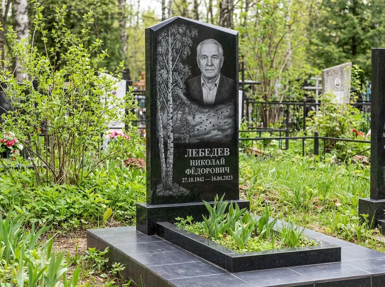 Памятник с гравировкой берёзы: вертикальная стела со скошенным верхом — берёза и стая птиц в небе, гранитный цоколь с тёмной плиткой, работа «Лебедев» в Ижевске