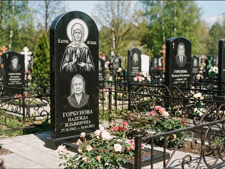 Памятник с гравировкой иконы: стела с арочным верхом и киотом под образ — гравировка образа Матроны Московской, гранитный цоколь с тёмной плиткой, работа «Ковалёв» в Ижевске
