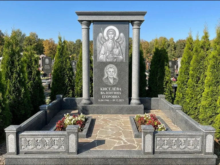 Памятник с гравировкой иконы: массивная стела с двускатным навершием-домиком — гравировка Николая Чудотворца, живая изгородь из туи, работа «Журавлёв» в Ижевске