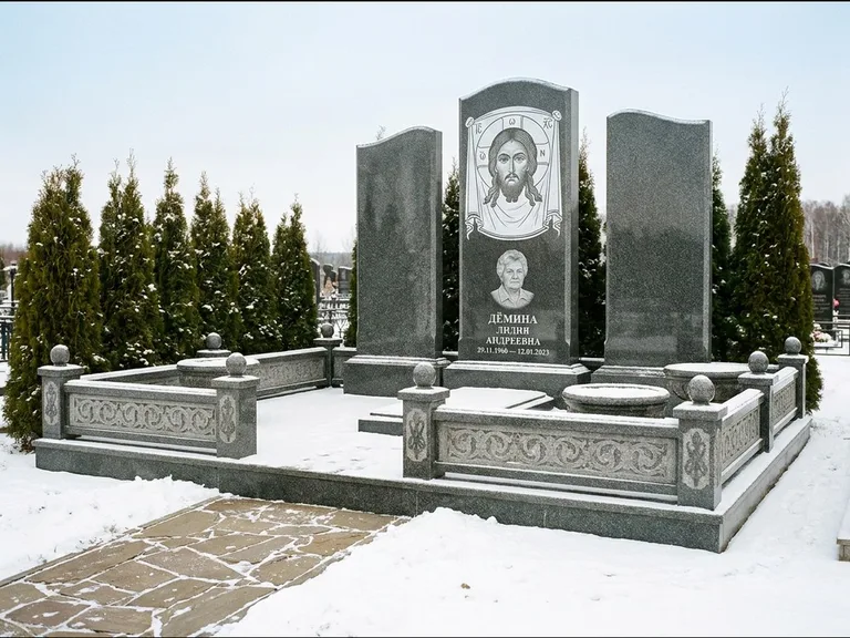 Памятник с гравировкой иконы: узкая вертикальная стела-пилон с ликом — икона в резной рамке-киоте, открытая лужайка без ограды, работа «Одинцов» в Ижевске