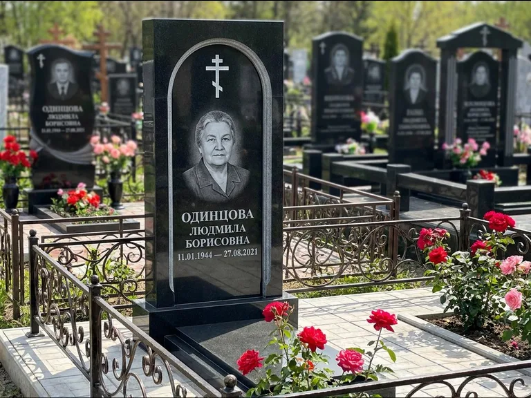 Памятник из чёрного гранита — скромная невысокая стела с крестом с терновым венцом, работа «Лаврентьева» в Ижевске