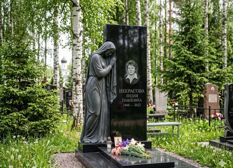 Гранитная фигура скорбящего мужчины у чёрной стелы в Ижевске